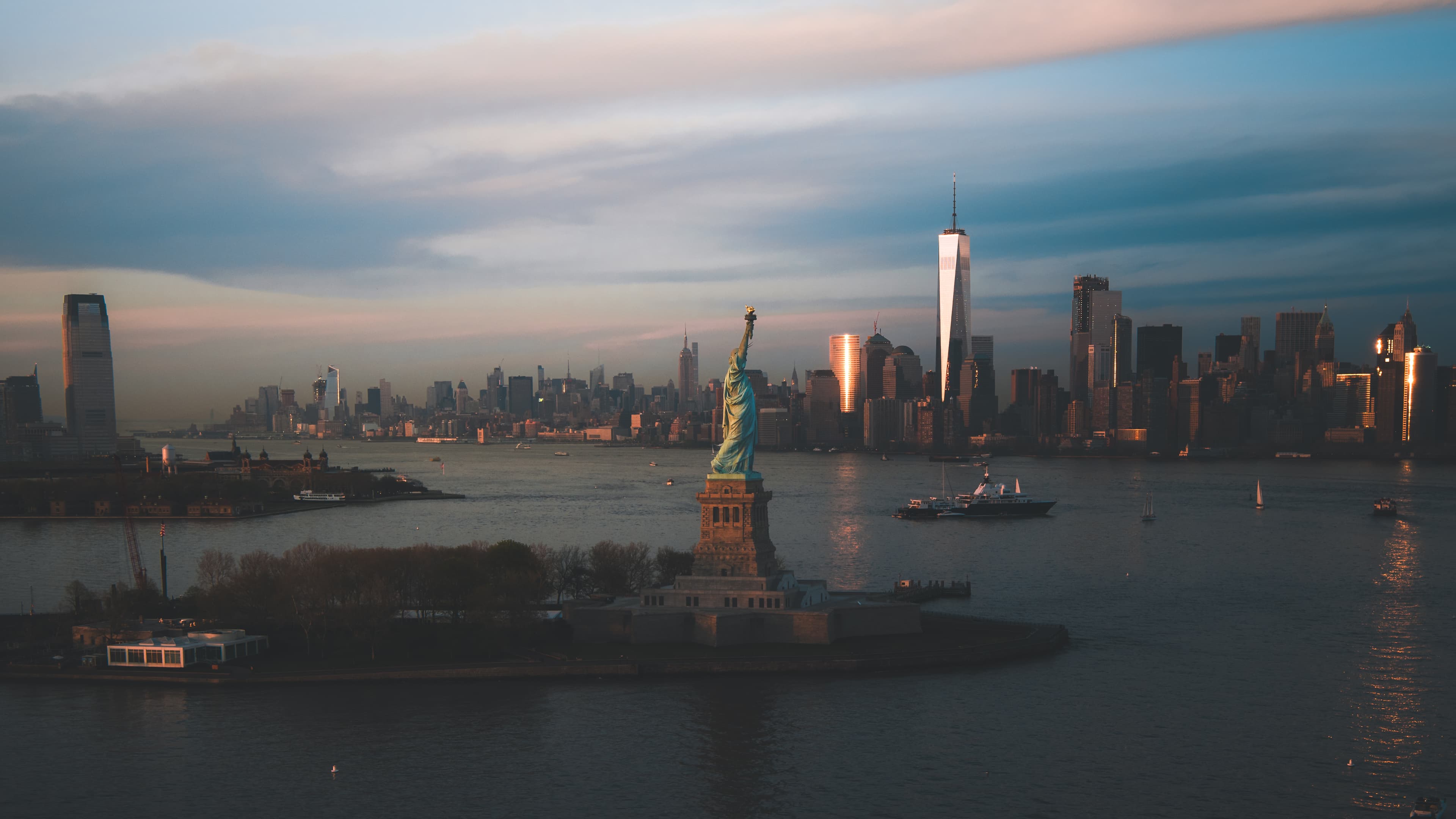 The Statue of Liberty and Lower Manhattan skyline at dusk.