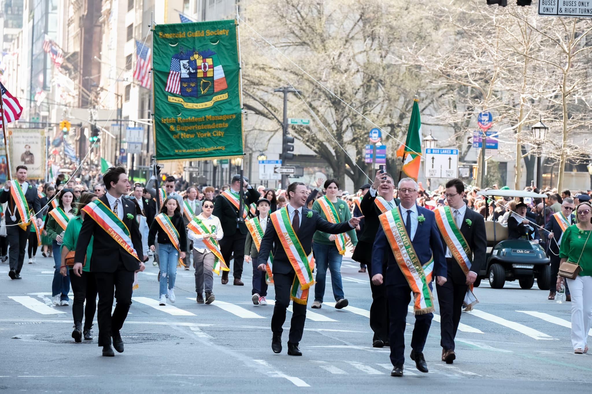 Emerald Guild Society members and banner moving through a crowded 2024 parade route in New York City.